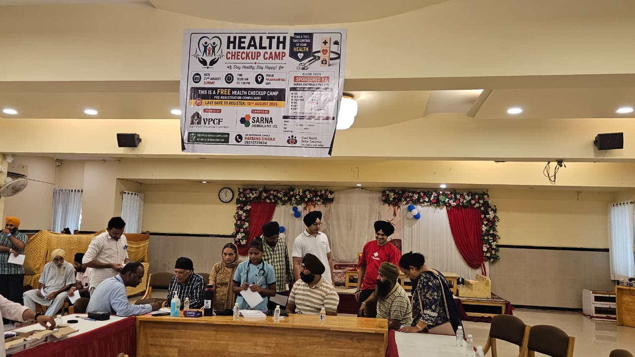 Medical consultations taking place beneath the Health Checkup Camp banner in Vapi